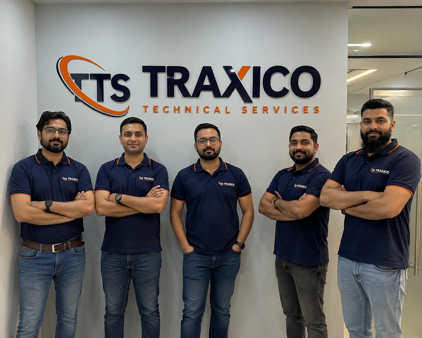 Five TRAXICO technicians in branded polo shirts at the company office in Trade Center First, Dubai